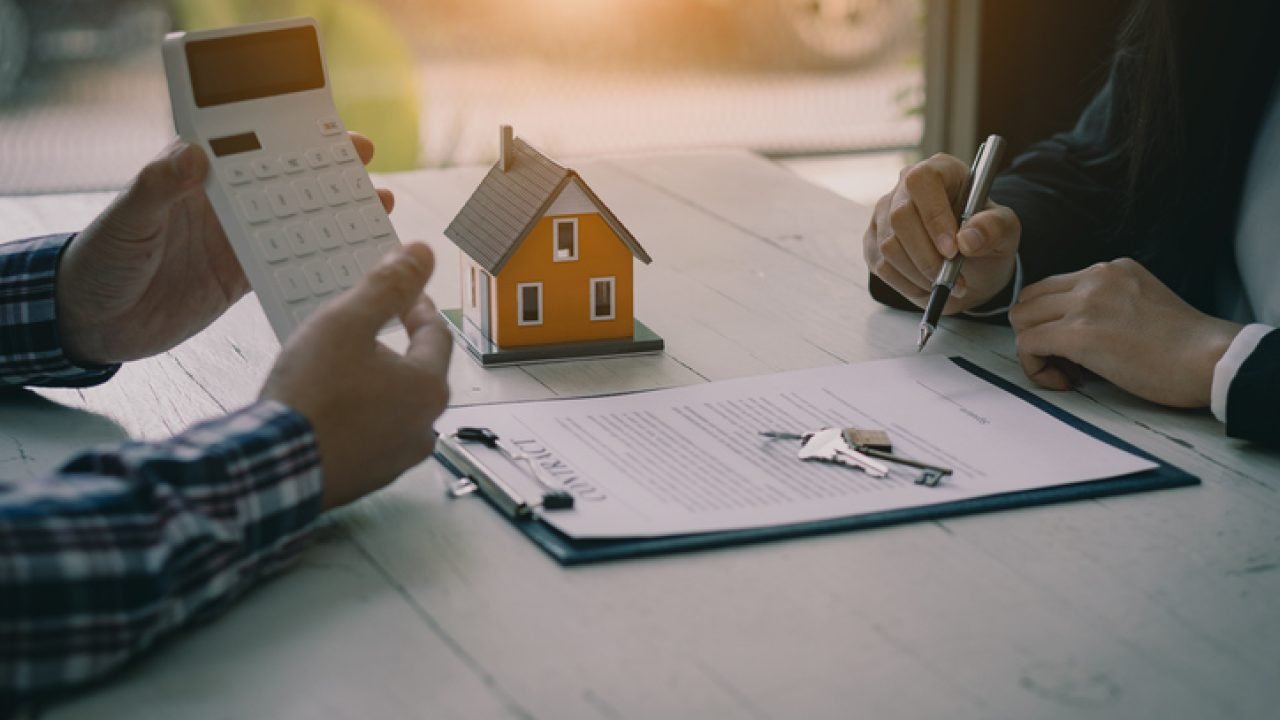 Real estate professionals offer their clients contracts to discuss home purchases, insurance or real estate loans. Home sales agents sit at the office with new home buyers in the office.