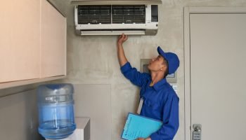 Young Asian technician checking conditioner in kitchen